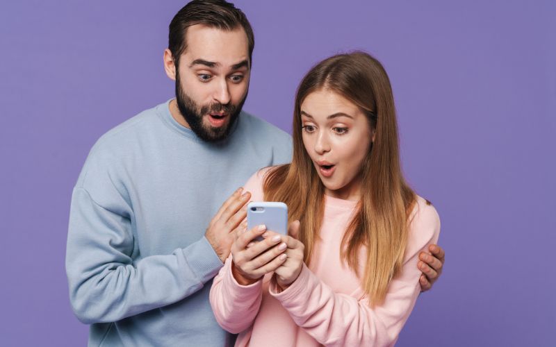 Pareja sorprendida al ver una oferta exclusiva en el celular, ejemplo del FOMO como estímulo emocional en marketing