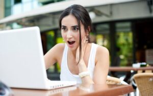 Mujer sorprendida al ver una oferta limitada en su laptop, ejemplo del efecto FOMO en marketing digital