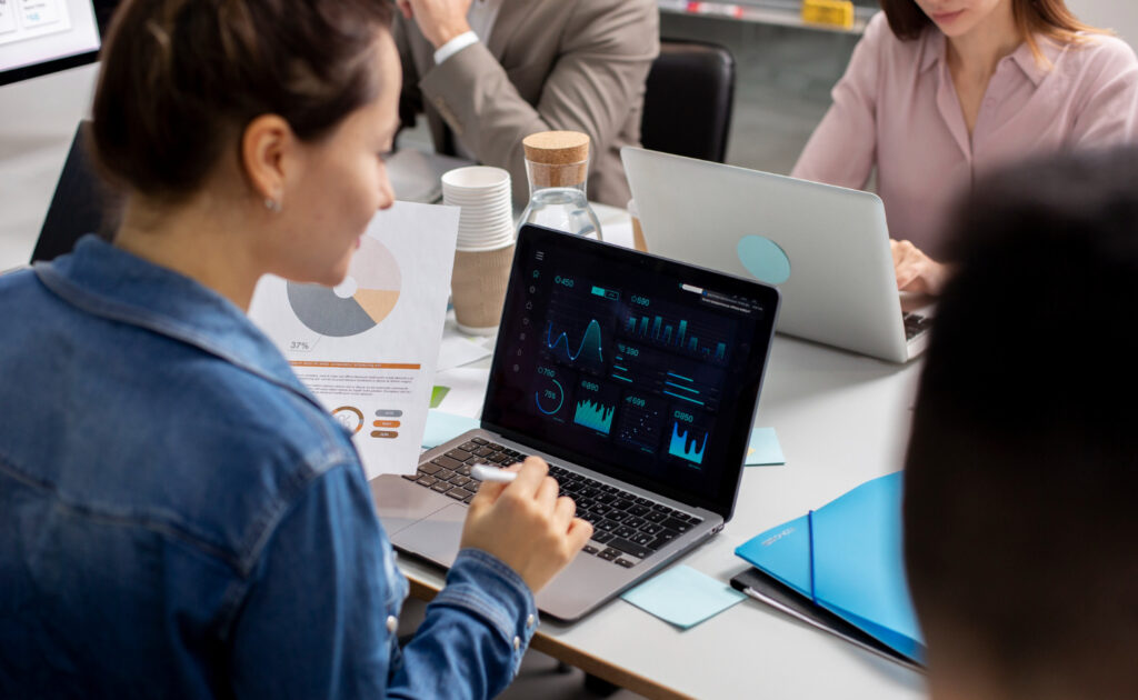 Una mujer trabaja en una computadora portátil mostrando gráficos y datos, para ilustrar los sectores a los que pertenecen las empresas medianas en México.