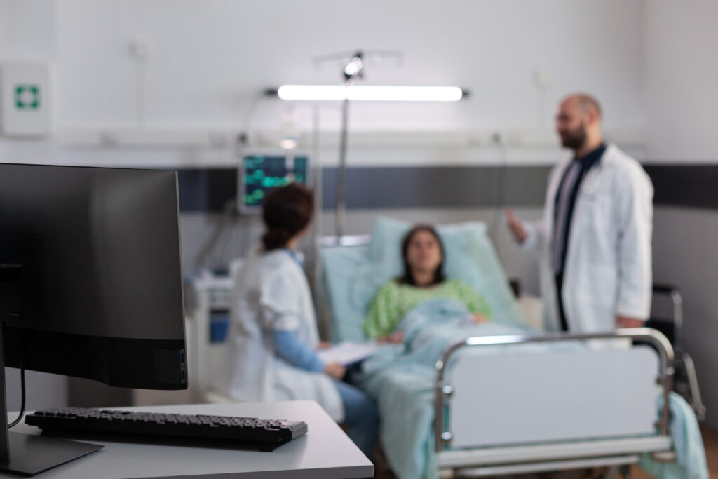 Vista de una habitación de hospital, que es una empresa mediana de servicios. Al fondo, una paciente es atendida por médicos que interactúan a su alrededor.