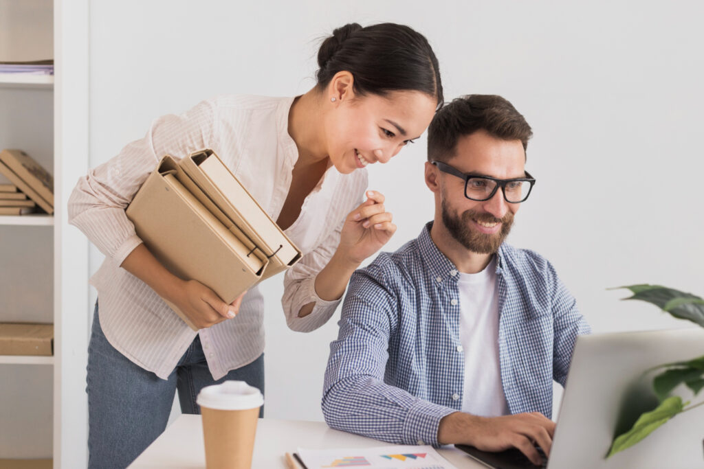 Dos colegas trabajan juntos en una laptop, mostrando un mindset emprendedor y colaborativo en un ambiente de oficina moderno y luminoso.