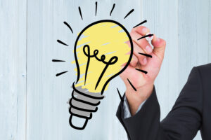 Una mano dibuja una bombilla brillante, símbolo de ideas innovadoras y generación de nuevas soluciones creativas que surgen de la mentalidad emprendedora.