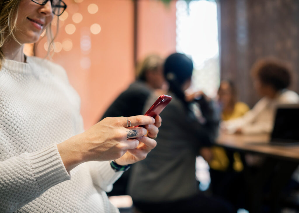 Mujer de cabello claro envía un mensaje de texto a través de su teléfono celular, para mantener activa su red de contactos.