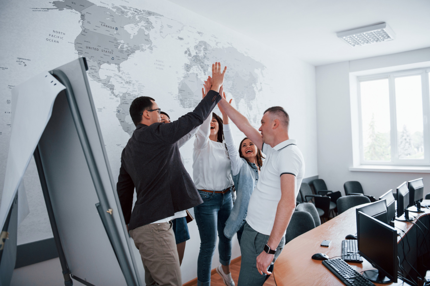 En un espacio de trabajo, un grupo de colaboradores junta sus manos en señal de triunfo, como parte de los resultados positivos que obtienen gracias a sus habilidades blandas.