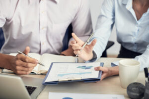 Manos que sostienen y revisan documentos con gráficas. La imagen ilustra una consultoría empresarial.