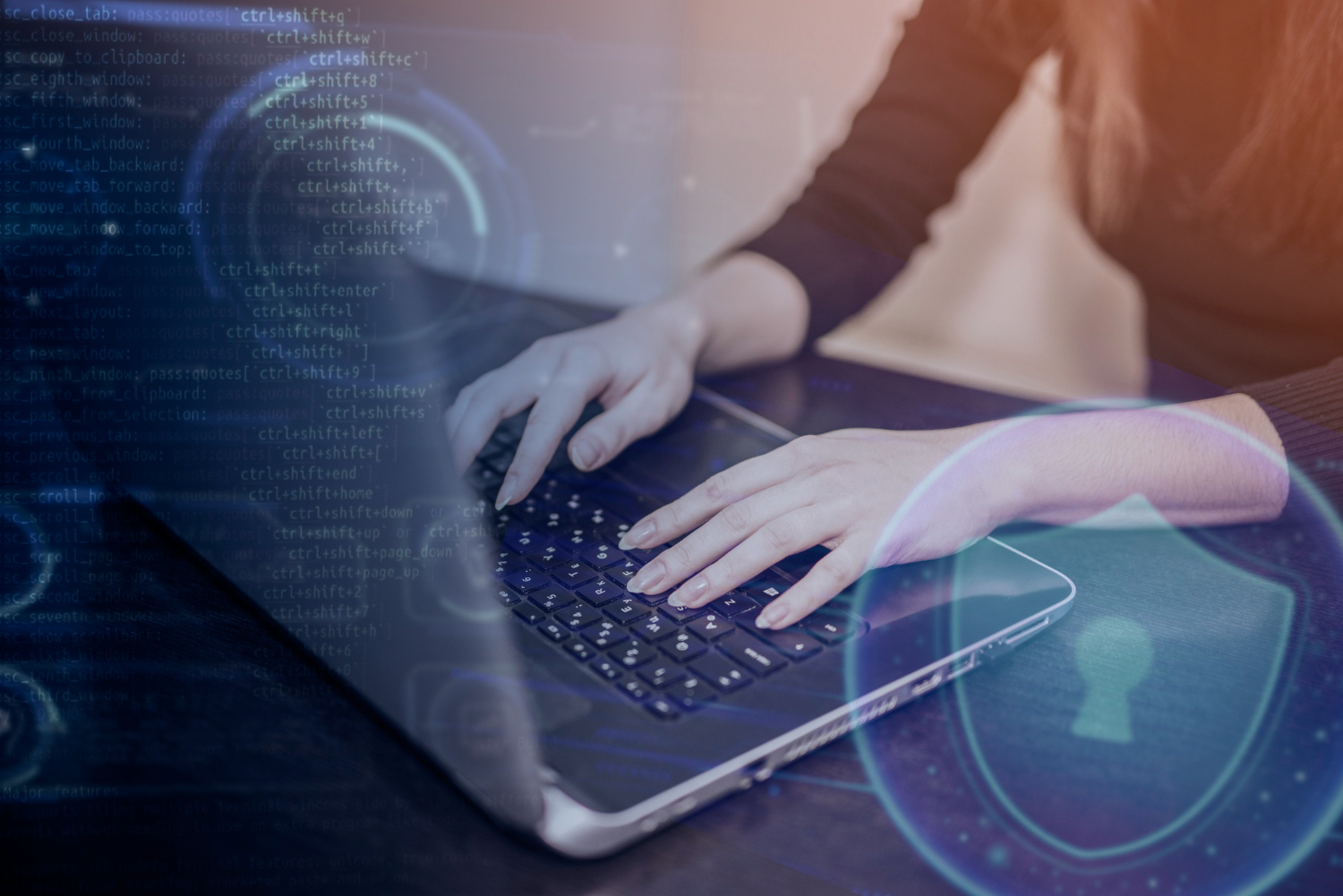 Vista de unas manos femeninas sobre un teclado de computadora. Se ve también un símbolo de escudo de seguridad que sirve para ilustrar la ciberseguridad.