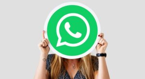 Mujer sostiene el logo de WhatsApp con ambas manos y lo muestra en lugar de su rostro.