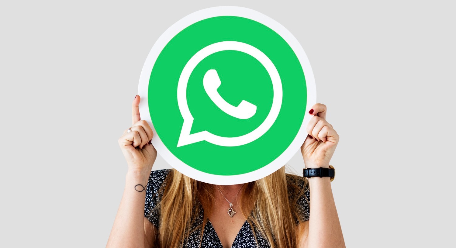 Mujer sostiene el logo de WhatsApp con ambas manos y lo muestra en lugar de su rostro.