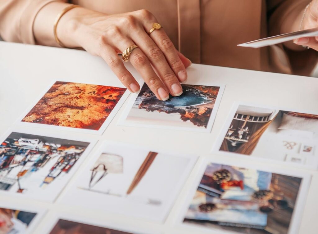 Vista de las manos de una mujer que acomoda fotos impresas sobre un tablero.