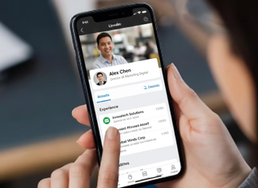 Vista de una mano que sostiene un teléfono celular donde se ve un perfil de LinkedIn