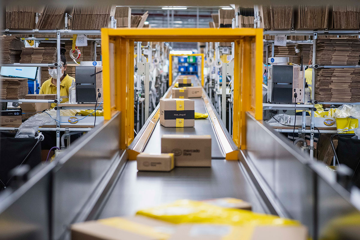 Vista de un centro de distribución de Mercado Libre. Los paquetes pasan por una banda automatizada.