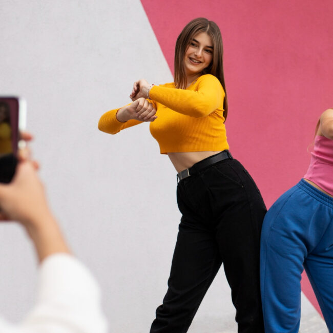 Mujeres bailan una coreografía mientras otra las graba con un teléfono celular. La imagen ilustra los contenidos que se suben a TikTok