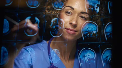 Una mujer con vestimenta de personal médico, ve imágenes del cerebro humano, para representar avances de la IA en todas las industrias. 