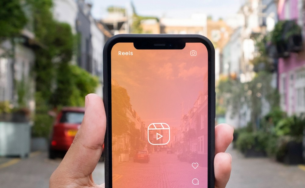 Un teléfono celular, con su sesión de instagram abierta, enfoca un  paisaje para grabarlo. 