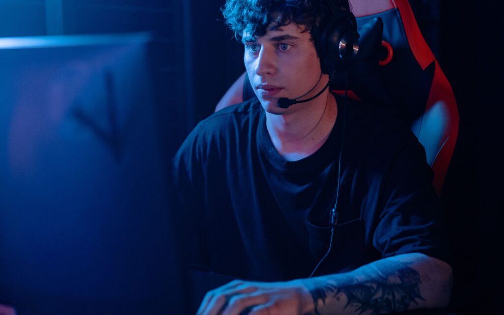 Hombre joven jugando videojuegos en su computadora durante horas, expuesta a luz azul asociada a fatiga visual y cansancio ocular